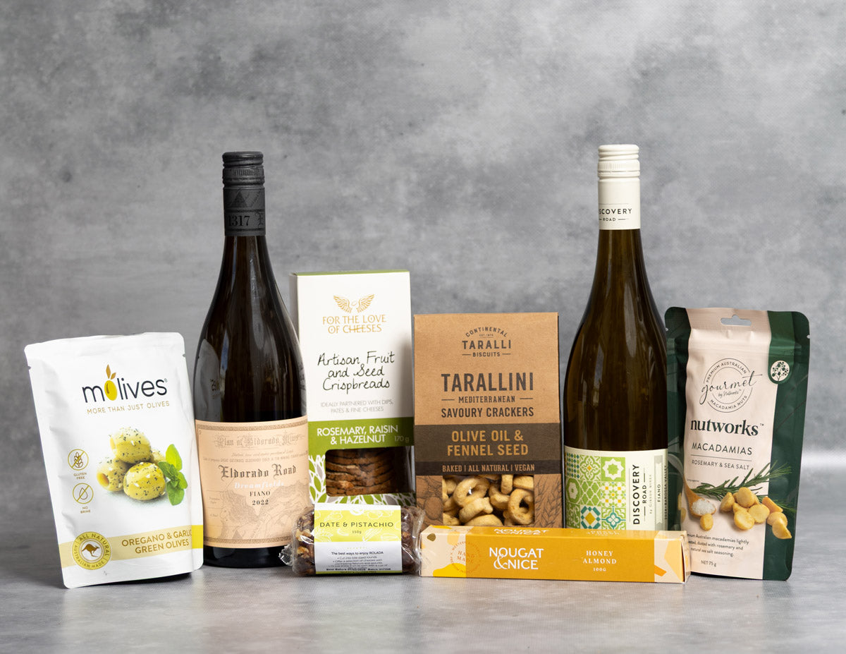 Fiano Lover Hamper. Assorted food products including wine bottles and packaged snacks on a gray surface with a gray background.