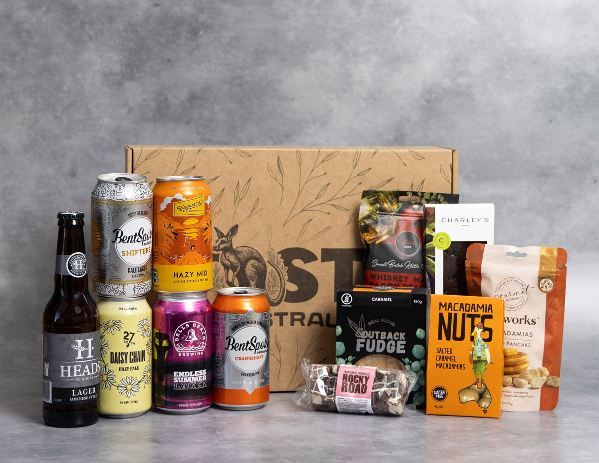 Beer and Nuts Hamper. Collection of beer cans and snacks in front of a cardboard box with a brand logo on a gray background