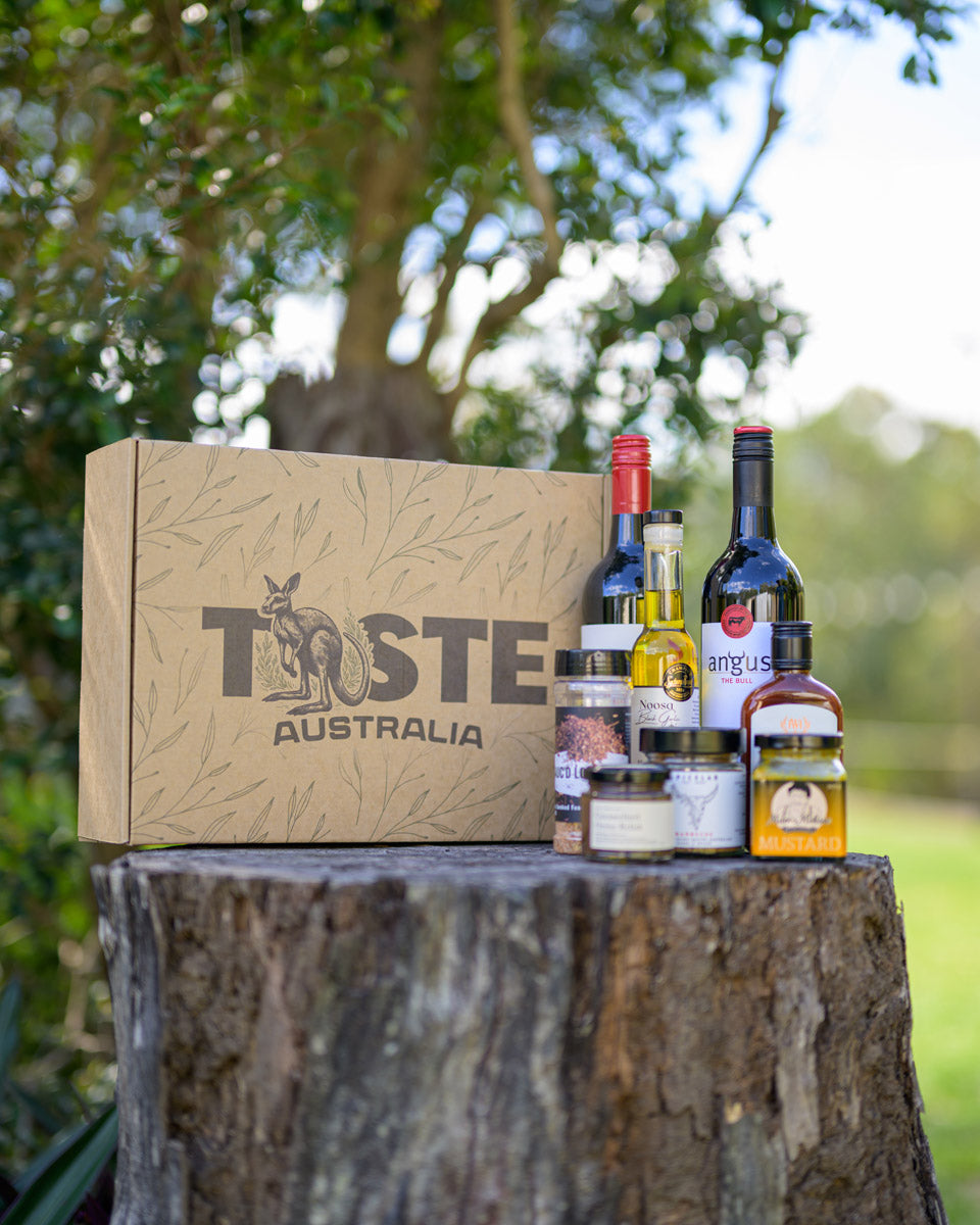 Taste Australia box with wine and snacks on a tree stump outdoors